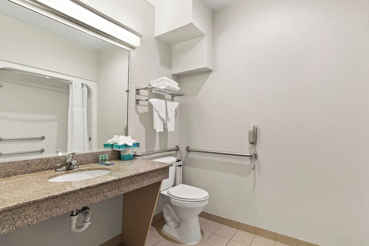 Une salle de bain avec un comptoir en granit, des toilettes blanches, un sèche-mains et un porte-serviettes.