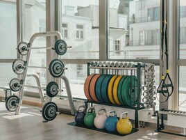 Uma academia com equipamentos de musculação, kettlebells e faixas de resistência.
