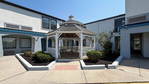 A gazebo with a white roof and wooden beams, surrounded by a white fence and small bushes. - Motel 6 Newark, DE (Newark)