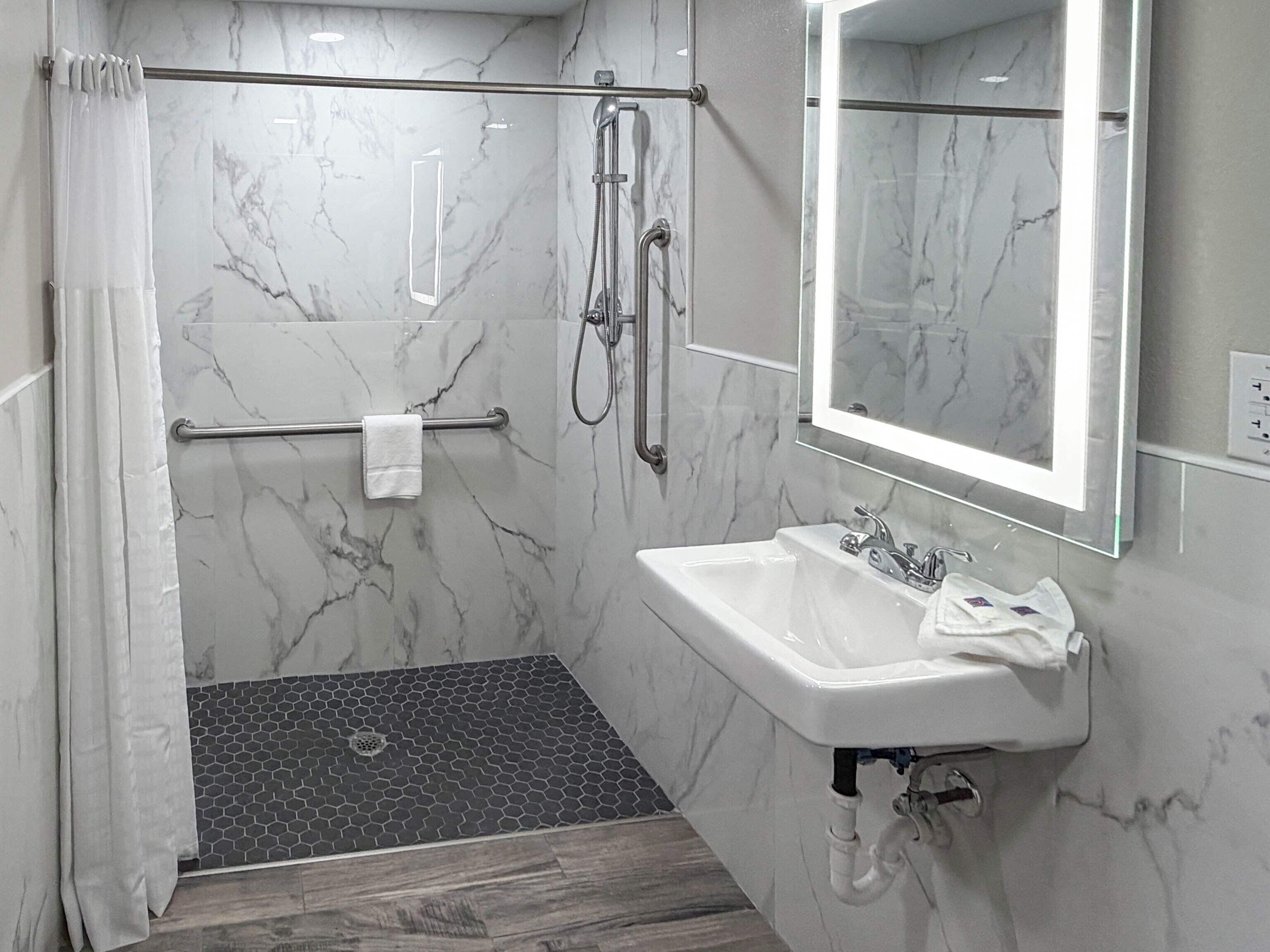 A bathroom with a shower, a sink, and a mirror.