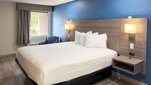 A hotel room with a large bed, bedside lamps, a chair, and a window with curtains. - Motel 6 Newark, DE (Newark)