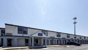 A motel with a covered entrance, multiple windows, and a parking lot with a few cars. - Motel 6 Newark, DE (Newark)