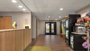 A hotel lobby with a reception desk, a refrigerator with snacks, and a microwave.