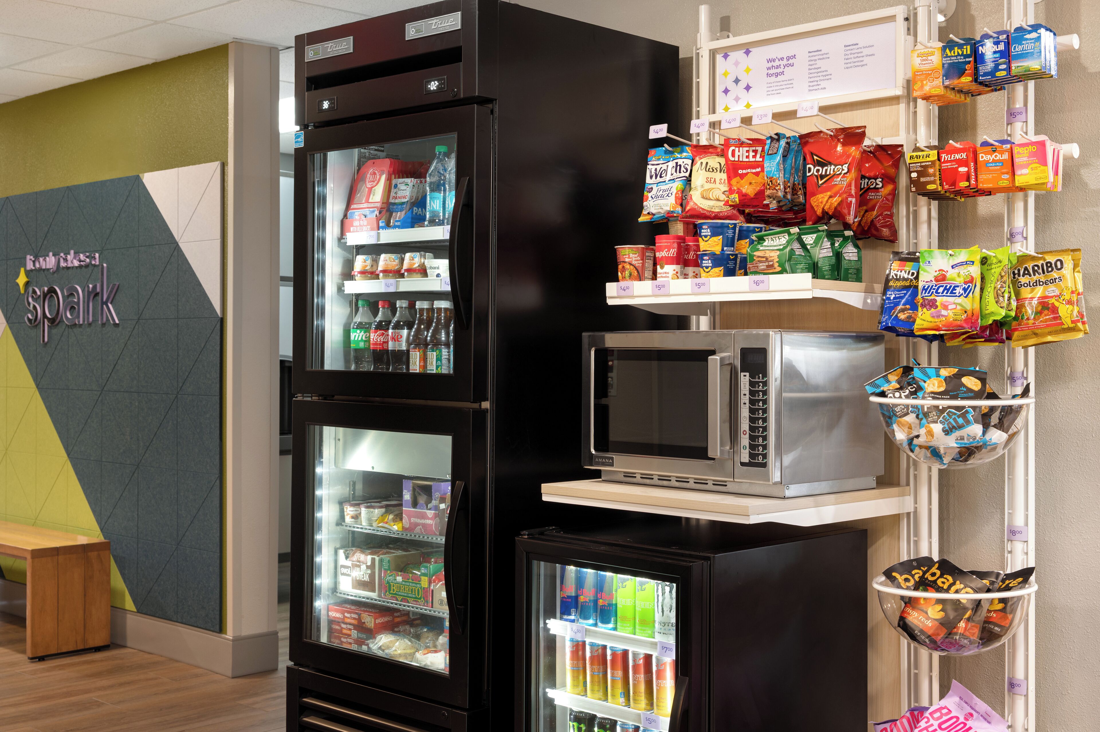 Zona de máquinas expendedoras con aperitivos y bebidas, un microondas y un refrigerador.