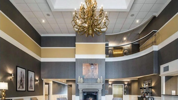 Un hall espacioso con una gran lámpara de araña, una chimenea y una zona de estar con muebles modernos.