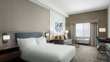 A hotel room with a large bed, a desk, a chair, and a view of the outdoors.