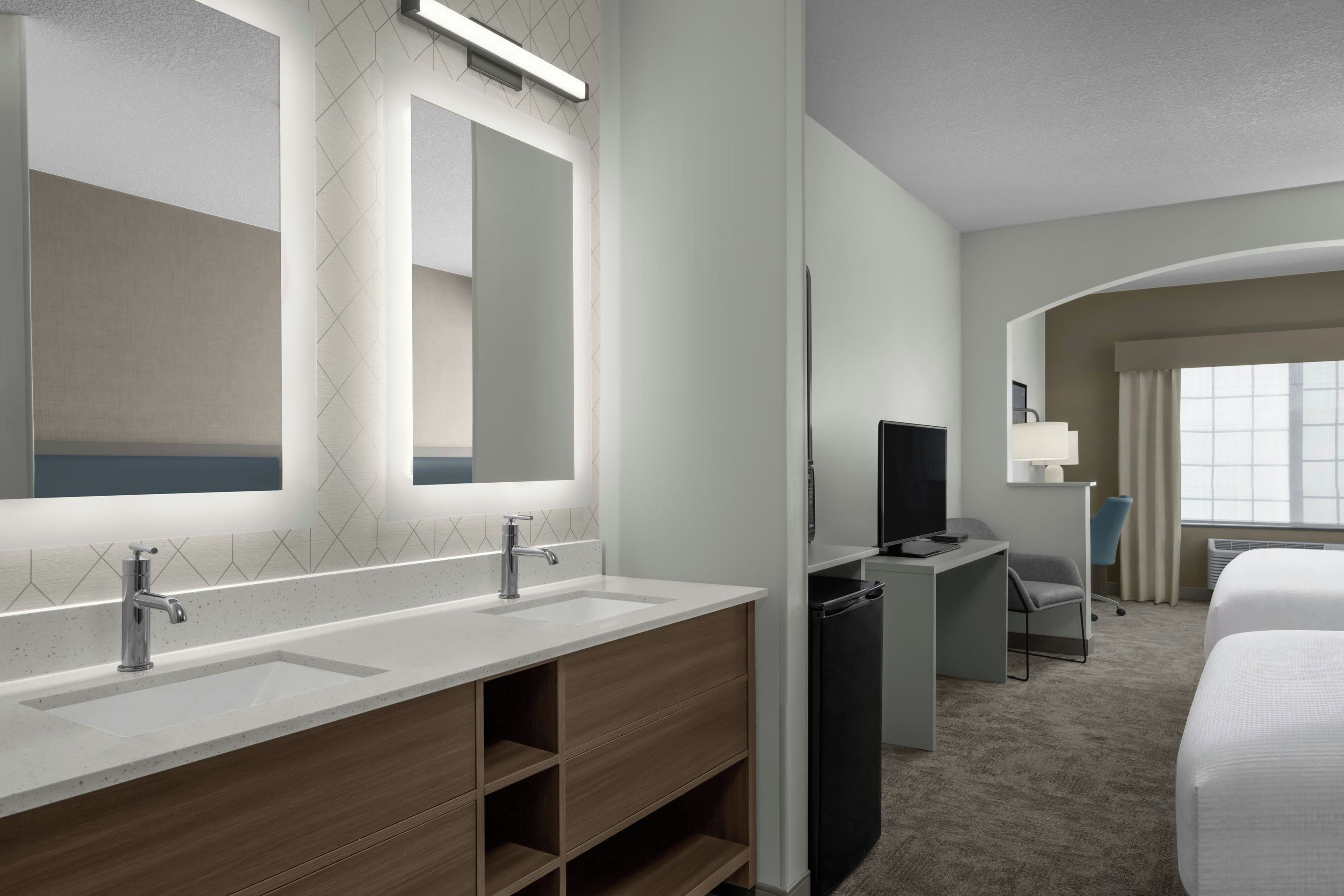Un baño de hotel con lavamanos doble, espejo y zona de ducha.