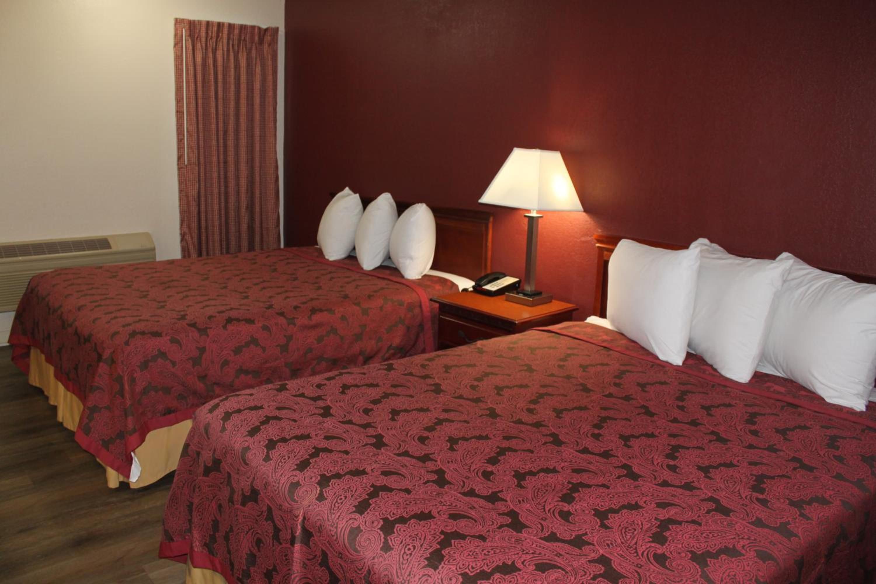 A hotel room with two beds, a nightstand, a lamp, and a telephone.