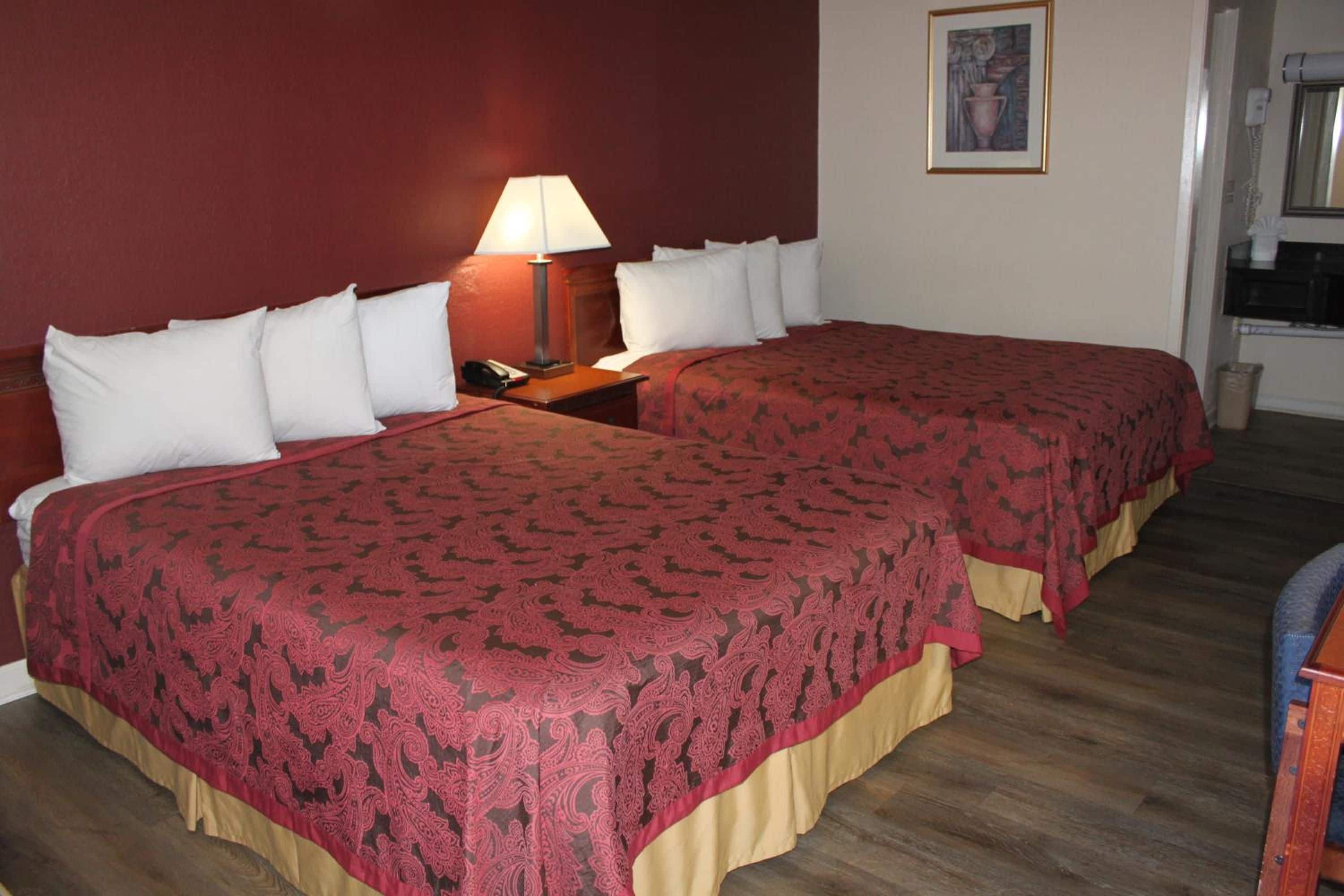 Une chambre d’hôtel avec deux lits, une table de chevet, une lampe et un tableau au mur.