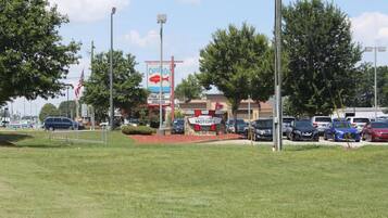 A parking lot with several cars, a building with a sign for 'Captain's Classic Luxury Motors', and a large billboard advertising a seafood restaurant.