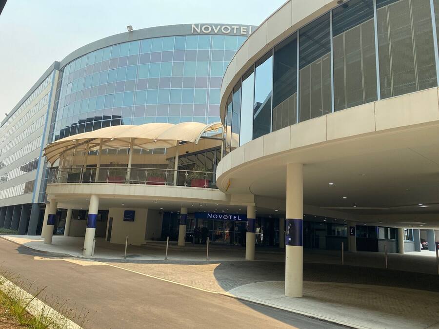 A Novotel hotel with a modern glass facade, a covered entrance area, and a spacious outdoor seating area.