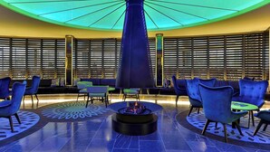 Un espace détente doté d’un foyer central, de différents types de sièges et d’un sol à motifs.