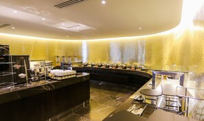 A modern hotel lobby with a curved reception desk, a buffet area with food stations, and a seating area with tables and chairs. - Novotel Sydney West HQ Hotel (Rooty Hill)