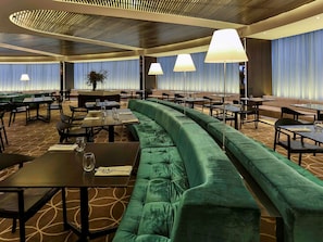 A modern restaurant with a green upholstered sofa, dining tables, and ambient lighting. - Novotel Sydney West HQ Hotel (Rooty Hill)