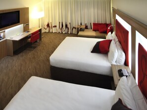 A hotel room with two beds, a desk, a TV, and a curtain with a unique design. - Novotel Sydney West HQ Hotel (Rooty Hill)