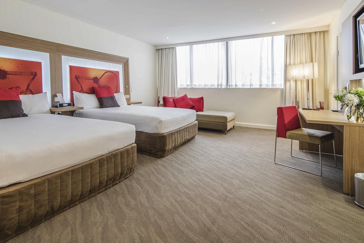 Una habitación de hotel con dos camas, un escritorio, una silla y un televisor.