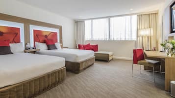 A hotel room with two beds, a desk, a chair, and a TV.