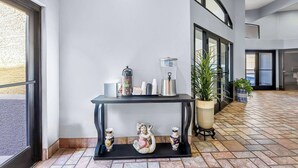 A modern lobby with a black console table, decorative angel figurines, a potted plant, and a tiled floor. - Days Inn by Wyndham Buckeye (Buckeye)