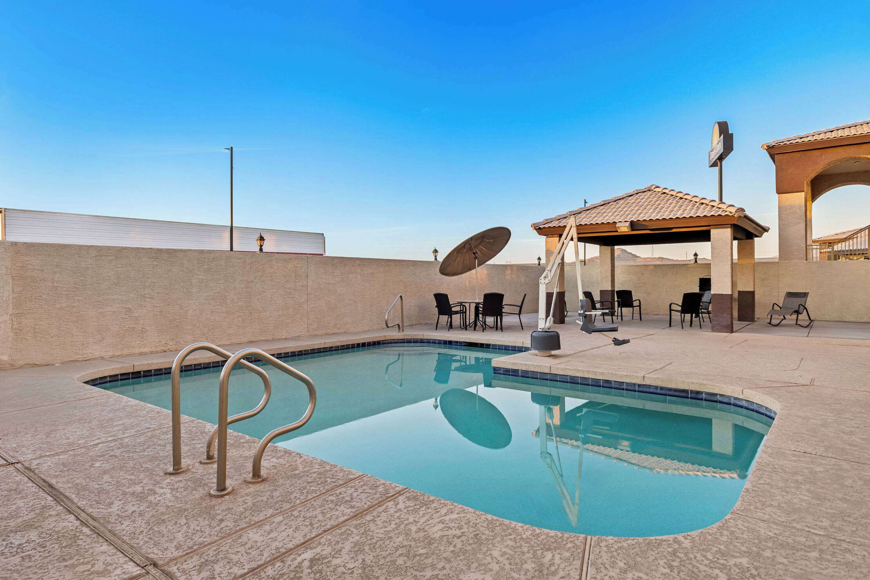 A swimming pool with a tiled edge, surrounded by lounge chairs and a covered seating area.