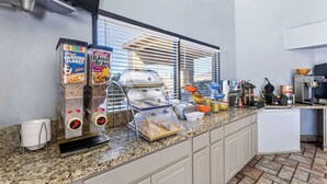 A breakfast bar with cereal dispensers, a grill, and various kitchen appliances. - Days Inn by Wyndham Buckeye (Buckeye)