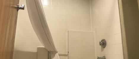A bathroom with white tiled walls, a bathtub, a shower curtain, and a towel rack.