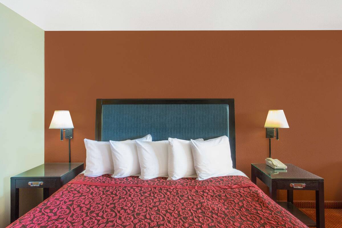 A hotel room with a bed, two bedside tables, a telephone, and lamps.
