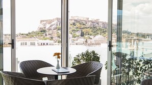 A room with a view of a historic cityscape, including a prominent ancient fortress and a modern building.
