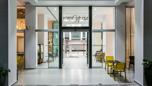 The entrance to a hotel with a modern design, featuring glass doors and a reception area visible through the entrance.