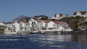 Une propriété située au bord de l’eau, comprenant plusieurs maisons, un quai avec des bateaux et une côte rocheuse.