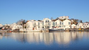 Une propriété située au bord de l’eau, comprenant plusieurs maisons, un quai avec des bateaux et un ciel d’un bleu limpide.