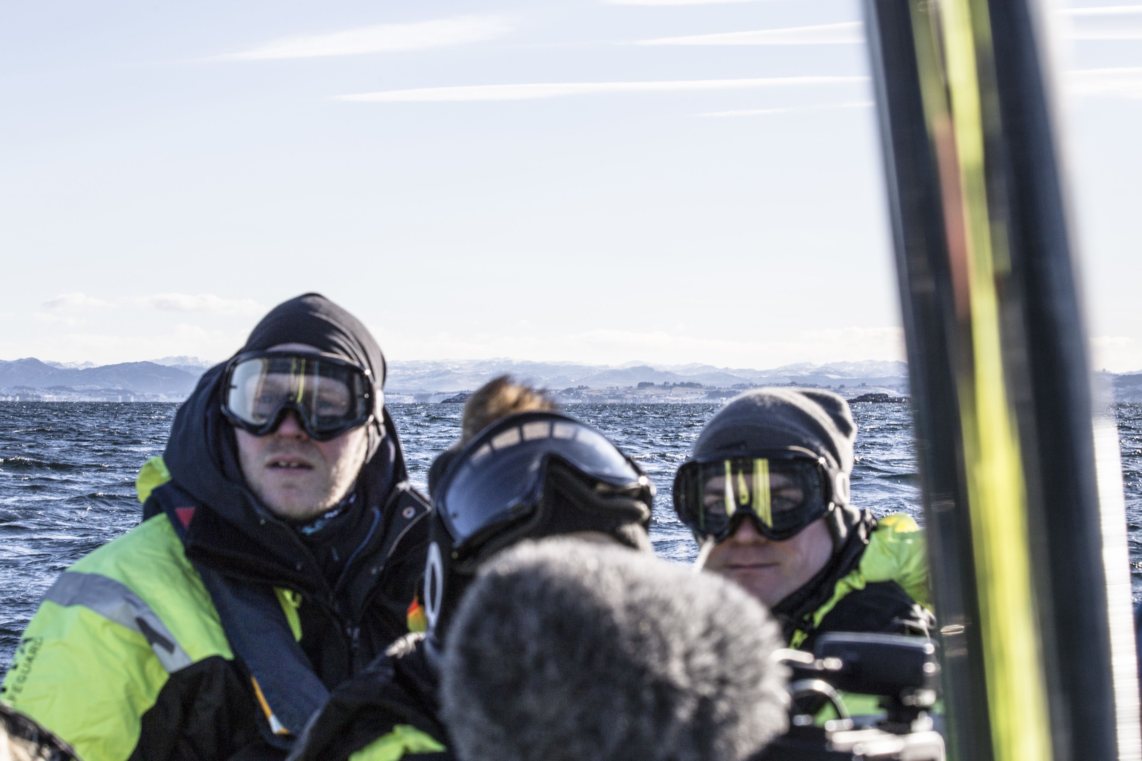 A group of people in a boat with a snowy landscape in the background.