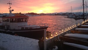 Un bateau était amarré dans une marina, les bancs étaient recouverts de neige et une rambarde longeait le quai.