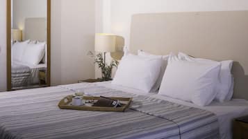 A neatly made bed with white linens, a tray with a glass of water, a brown bag, and a pair of glasses on the bed.
