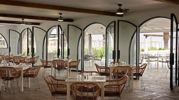 An indoor dining area with high arched ceilings, wicker chairs, and tables.