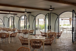 An indoor dining area with high arched ceilings, wicker chairs, and tables. - Kassandra Palace Seaside Resort (Kassandra)