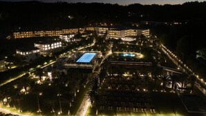 Un gran resort con varias edificaciones, una piscina e iluminadas sendas.