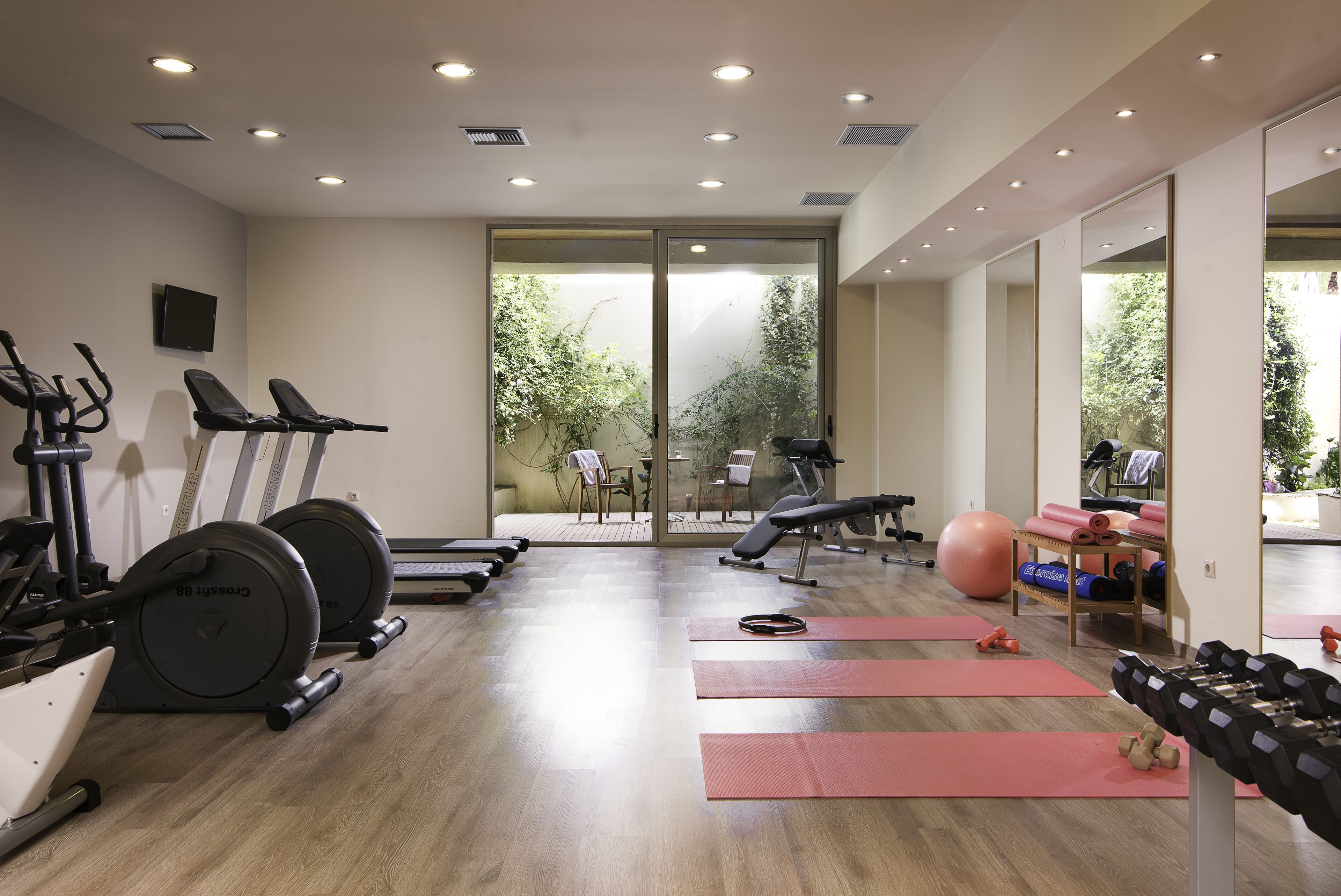 A gym with cardio equipment, yoga mats, and dumbbells.