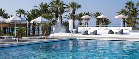 Una piscina techada, una piscina al aire libre, sombrillas