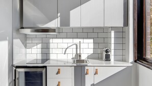 Una cocina compacta con armarios blancos, horno integrado y una ventana que proporciona luz natural.