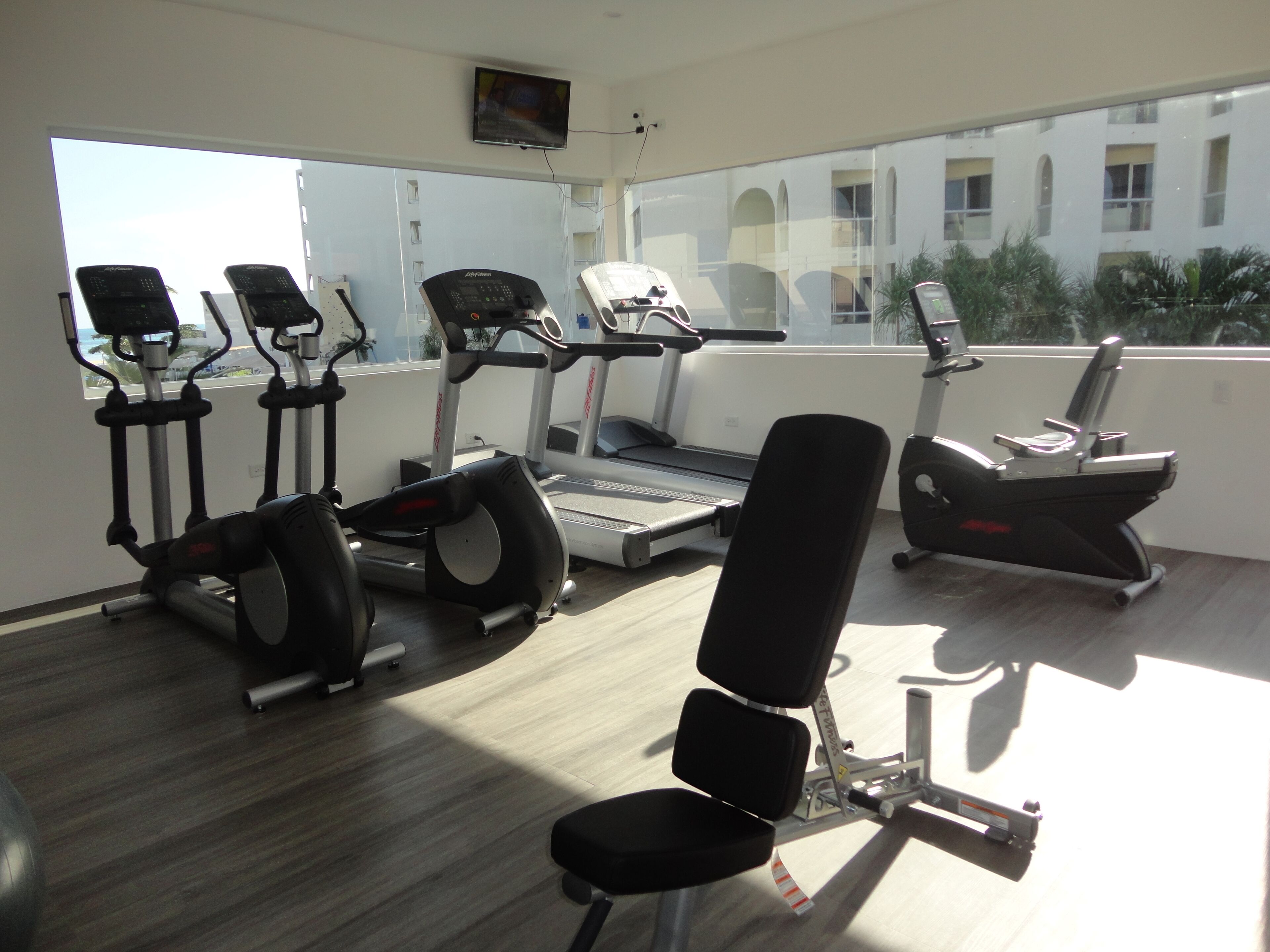 A gym with treadmills, elliptical machines, and a stationary bike.