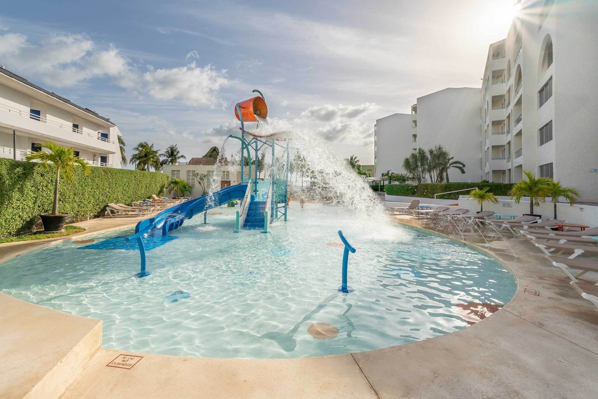 A swimming pool with a water slide and a water fountain.