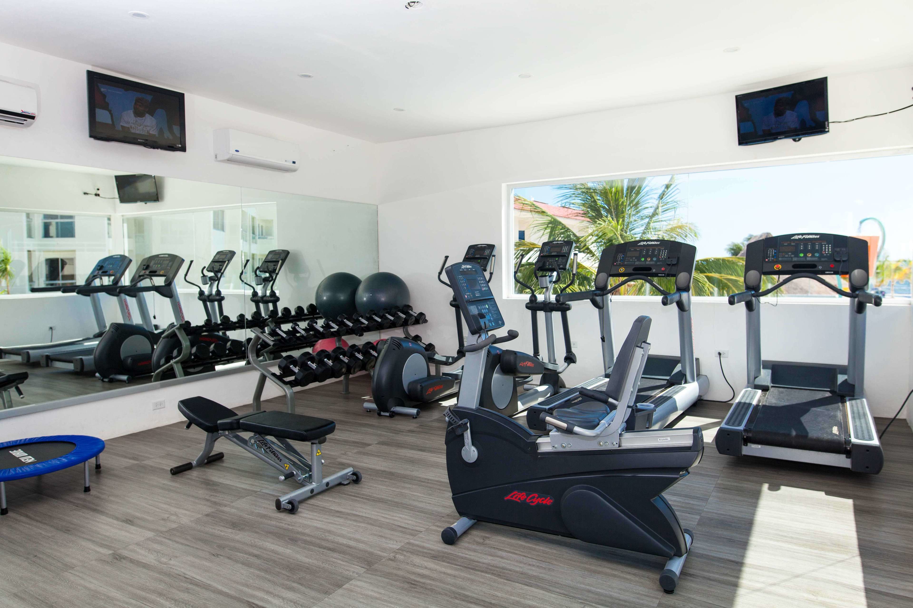 A gym with treadmills, elliptical machines, and a trampoline.