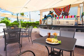An outdoor dining area with a table set for two, a beverage, and a plate of food. -  Aquamarina Beach Hotel (Cancun)