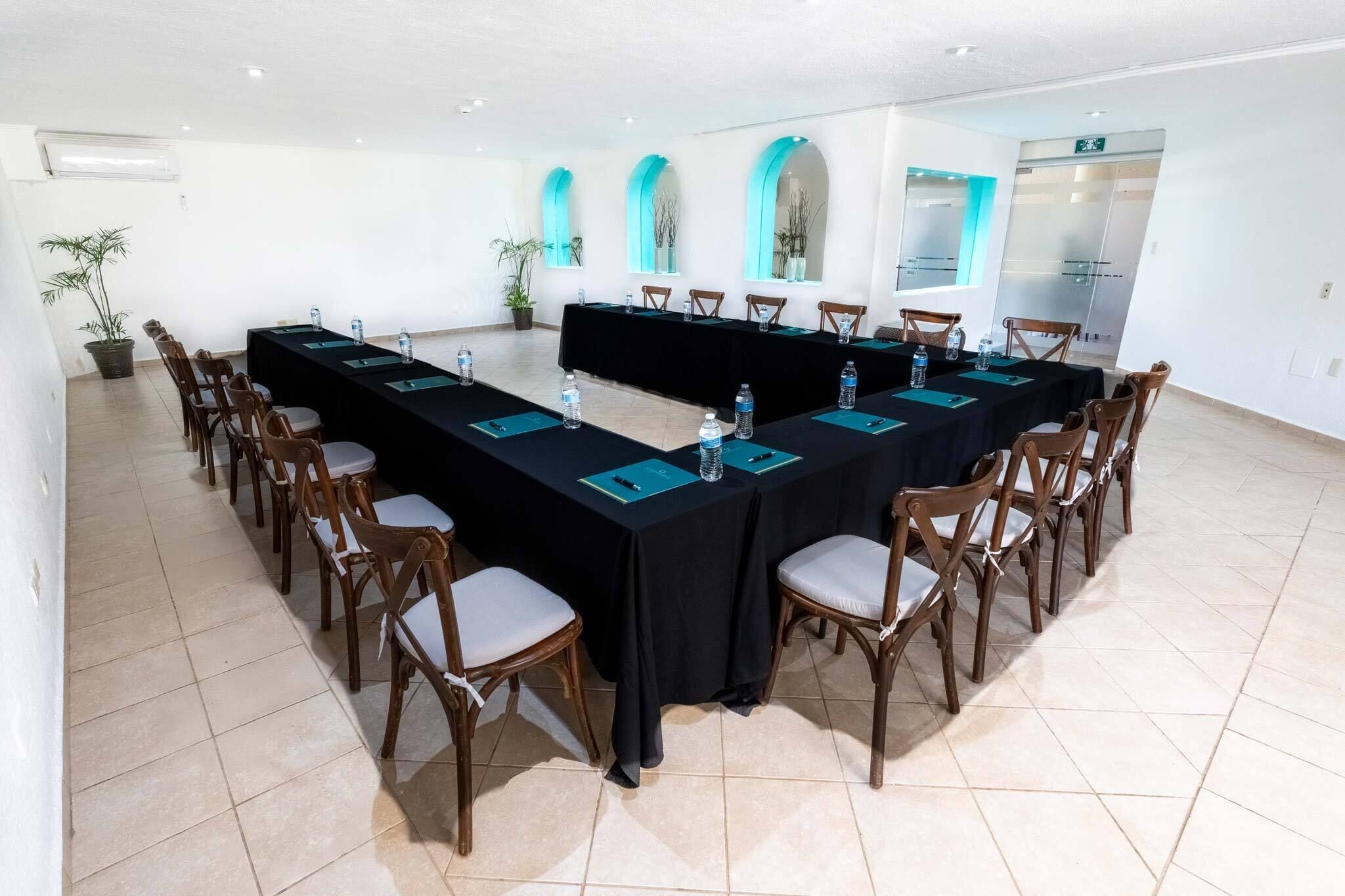 Una sala de conferencias con una larga mesa, sillas y plantas en macetas.