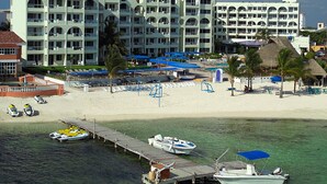 Un resort con spiaggia, piscina e molo con barche.