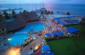 A resort with a large swimming pool, lounge chairs, and a beach area with boats. -  Aquamarina Beach Hotel (Cancun)