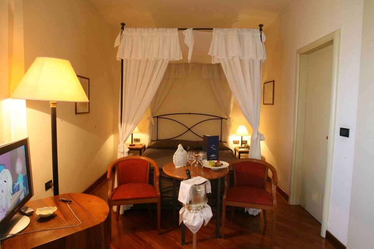 Ein Hotelzimmer mit einem Bett, einem Tisch mit Stühlen, einer Lampe und einem Fernseher.