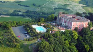 An aerial view of a large building with a swimming pool, surrounded by lush greenery and rolling hills. - Hotel Monte del Re (Dozza)