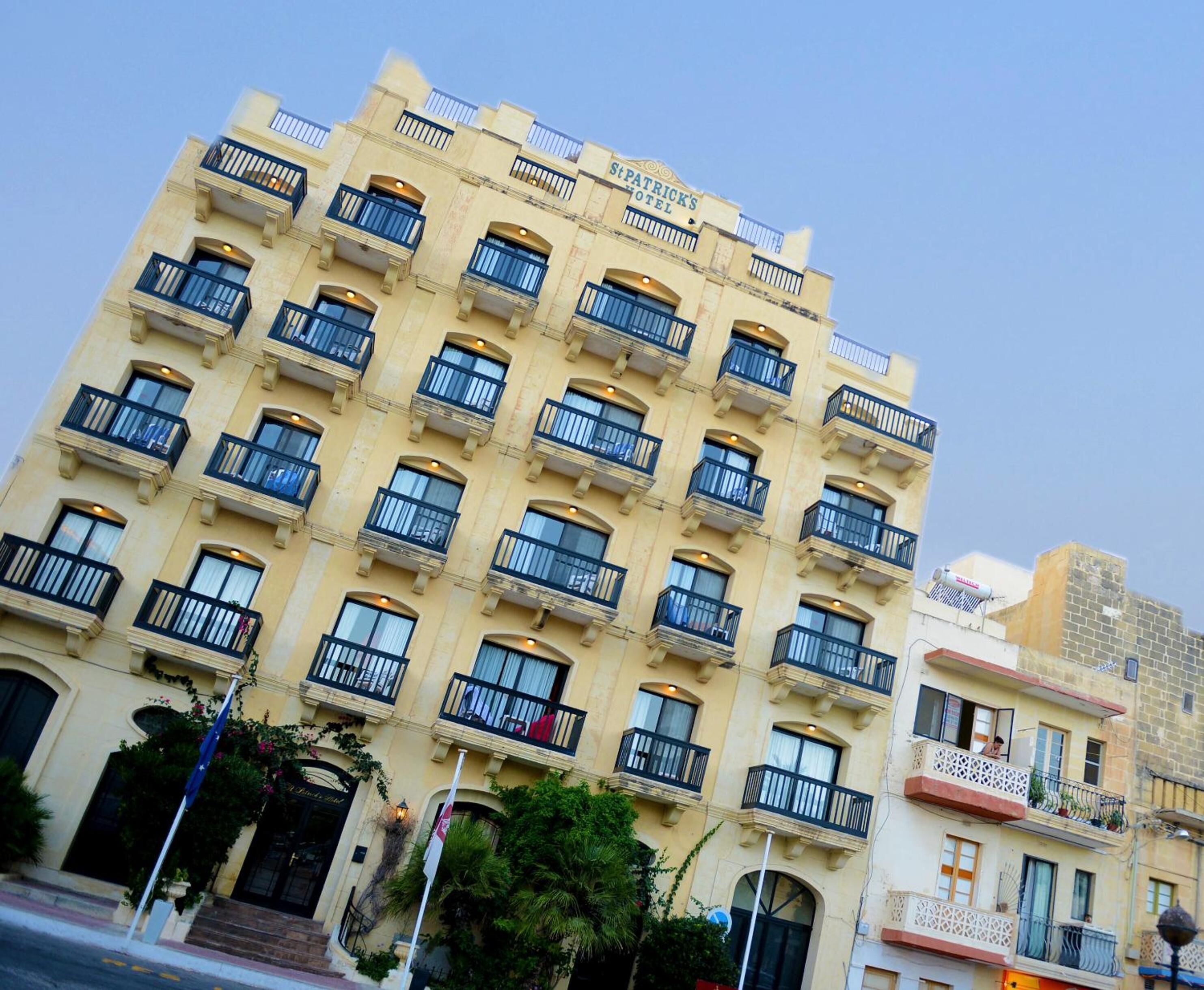 Un hotel de diversos pisos amb balcons, un senyal ben visible i un cel blau.