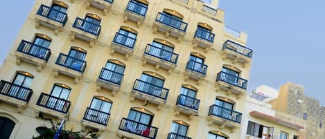 A multi-story hotel with balconies, a prominent sign, and a clear sky.